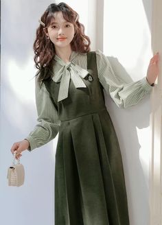 Faux two-piece layered dress with a stripe blouse with two buttons and a tie-up neckline, and a solid colored pinafore dress with a varsity embroidered badge, elastic waist and waist ties. S: 35.5" chest, 27" waist, 42" lengthM: 37" chest, 28.5" waist, 42" lengthL: 38.5" chest, 30" waist, 42" length Women Things, Stripe Blouse, Old Fashion Dresses, British Outfits, Layered Dress, Ladies Dress, Layer Dress, Pinafore Dress, Overall Dress