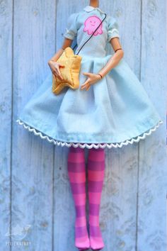 the doll is wearing a blue dress and holding a yellow purse with pink striped socks