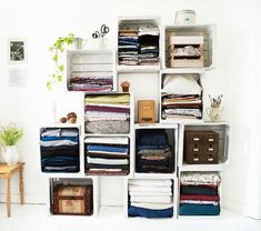 a room filled with lots of clothes and boxes on top of eachother in front of a white wall