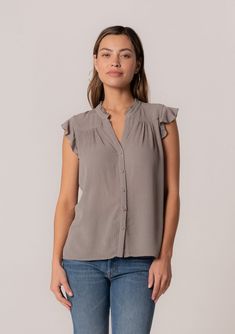 [Color: Cement] A front facing image of a brunette model wearing a grey crinkle gauze short sleeve flutter top with a button front and a ruffled neckline. Summer Solid Blouse With Crinkle Texture, Casual Blouse With Ruffle Sleeves And Button Closure, Summer Crinkle Texture Button-up Tops, Chic Ruffle Sleeve Rayon Blouse, Chic Flowy Button-up Top, Chic Rayon Blouse With Ruffle Sleeves, Relaxed Fit Blouse With Ruffle Sleeves, Chic Short Sleeve Blouse With Crinkle Texture, Chic Crinkle Texture Blouse For Daywear