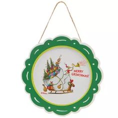 a green and white christmas ornament hanging from a string with a santa sleigh on it