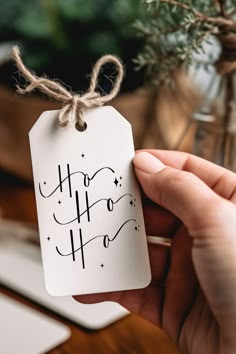 a hand holding a tag with the word ho ho written on it in black ink