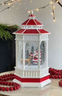 a white and red christmas lantern on top of a table next to some candy balls