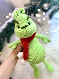 a crocheted green stuffed animal with a red scarf around it's neck