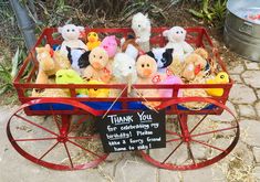 a red wagon filled with stuffed animals sitting on top of a stone floor next to a sign