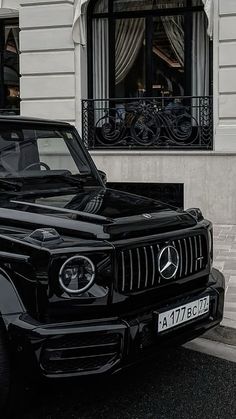 a black mercedes benz is parked in front of a building