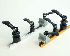 three metal handles are attached to a piece of wood with two black handles and one yellow handle