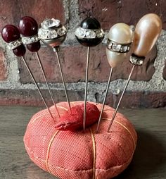 a pin cushion with pins in it sitting on a table next to a brick wall