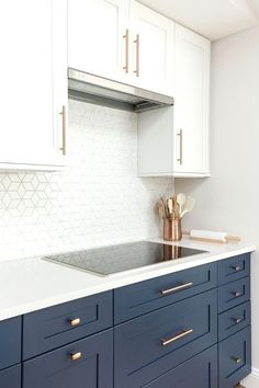 a kitchen with white and blue cabinets and gold pulls on the cabinet doors, along with brass handles