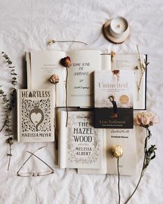 there are many books on the bed with flowers and hats next to each other,