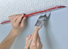 a person painting a wall with paint and a brush