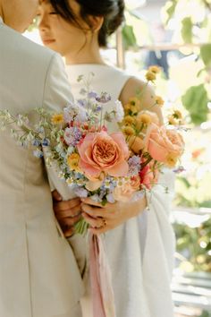 the bride and groom are holding each other close together with their bouquets in hand