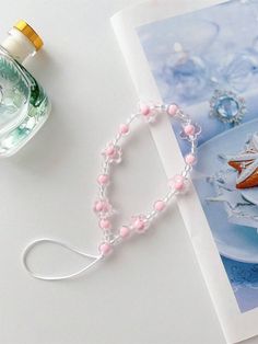 a book with some beads on it next to a glass bottle