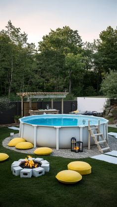 an above ground swimming pool surrounded by yellow pillows and fire pit in the back yard