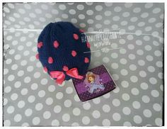 a blue hat with pink polka dots is next to a small purple and white box