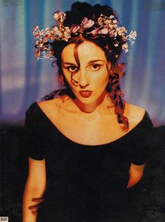 a woman with flowers in her hair wearing a black dress and posing for the camera