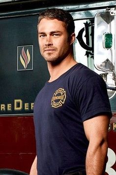 a man standing in front of a fire truck with his hands on his hips and looking at the camera