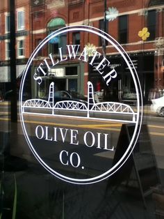 the logo for stillwater olive oil co is seen through a glass window in front of an old brick building