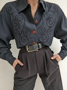 Faded black blouse with a beautiful, muted embroidered design at the front. Blouse has button closures up the front, a collared neckline and pleats at the sleeve cuffs.   100% rayon Tag reads TOTOnKo Recommended for size xs-l, depending on the desired fit. Modeled on an extra small frame. Please refer to the measurements listed below: Measures approximately: 20" shoulder to shoulder / 42" bust / 21" sleeve length / 28" shoulder to hemline There is some incredibly minor pilling. If you would like additional info or images prior to final sale purchase please reach out to vintage@naninstudio.com. Vintage items may come with minor flaws due to pre loved wear. Color of product may slightly vary compared to photo due to lighting. Please enjoy and appreciate this item with its character. Vintage Oc Clothes, Black Embroidered Blouse, Lady Outfits, 1970s Clothing, Pretty Clothing, Dr Closet, Character Poses, Formal Casual, Small Frame