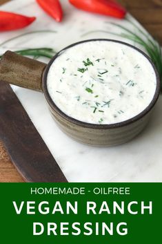 a bowl filled with ranch dressing on top of a cutting board next to red peppers