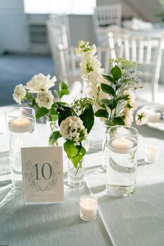 the table is set with white flowers and candles