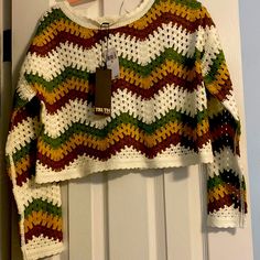 a crocheted sweater hanging on a door with a tag attached to the front