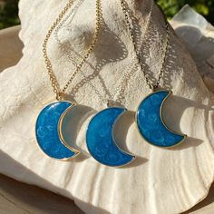 three blue moon pendants sitting on top of a shell