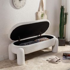 a white bench with an open suitcase on the floor in front of a cactus plant