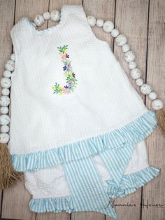 Welcome summer in this adorable seersucker swing back!  Cool summer swing back comes with a pretty aqua stripe ruffle hem with a matching edge around the neck .  Lovely long sash in back made with the same aqua stripe.  Bow is secured by an elastic loop and button.  Includes bloomer with the aqua stripe ruffles around the legs openings.  Entire outfit is 100 percent cotton with a cool 100 percent cotton lining.   Swing back can be personalized upon request.  Please give information for personalization along with font and thread color.  Sample in photos is done with the Floral Font using a single initial.   Prior to placing your order please feel free to contact me with any questions, comments or concerns about the item as there are no returns due to personalization. Floral Font, Welcome Summer, Embroidered Collars, Collared Sweatshirt, Cool Summer, Embroidery Fonts, 2 Piece Set, 100 Percent, Ruffle Hem