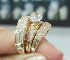 two gold wedding rings with diamonds on each one and an engagement ring in the other