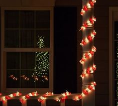 christmas lights on the outside of a house in front of a window and lit tree