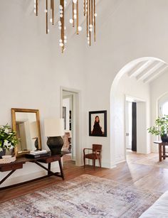 a living room filled with furniture and a chandelier hanging from the ceiling over a wooden floor