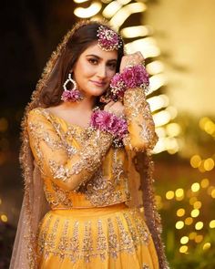 a woman in a yellow dress with pink flowers on her head and hands near her face