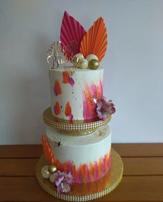 a three tiered cake decorated with orange, pink and purple flowers on a wooden table