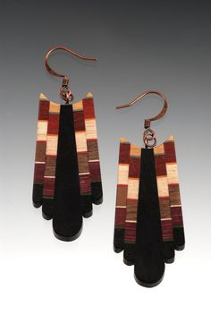 two pairs of wooden earrings with black and brown strips on them, hanging from metal hooks