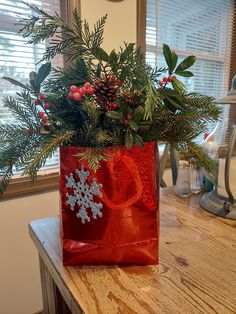 a red bag filled with pine cones and greenery on top of a wooden table