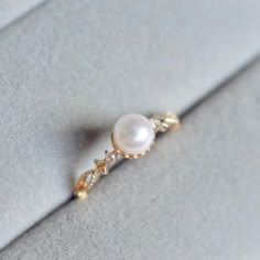 a pearl and diamond ring sitting on top of a piece of cloth