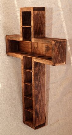 a wooden cross hanging on the wall with shelving unit in it's center