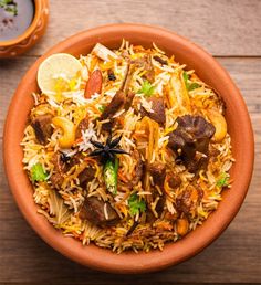 a bowl filled with rice and meat on top of a wooden table