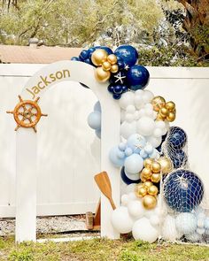 a white gate decorated with blue, gold and white balloons that spell out the name jackson