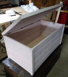 an open white box sitting on top of a wooden table in a room filled with boxes