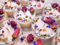 several bowls filled with different types of flowers on top of each other next to candles