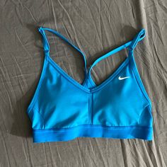 1. Brand: Nike 2. Color: Blue 3. Type: Sports Bra 4. Design: White Nike Swoosh Logo On The Left Side 5. Material: Likely A Blend Of Polyester And Spandex 6. Support: Great Support 7. Straps: Racerback Style 8. Fit: Compression Fit 9. Comfort: Breathable And Flexible 10. Activity: Suitable For Medium-Impact Workouts 11. Fabric: Moisture-Wicking 12. Chest Band: Elasticized Band For A Secure Fit 13. Coverage: Provides Good Coverage 14. Versatility: Great For Gym Sessions Or Outdoor Activities 15. D Nike Blue Sports Bra For Workout, Blue Nike Sports Bra For Training, Nike Blue Sports Bra With Moisture-wicking, Nike Blue Sports Bra For Training, Nike Blue Moisture-wicking Sports Bra, Nike Blue Activewear For Gym, Nike Blue Activewear For Workout, Nike Sporty Blue Sports Bra, Blue Sports Bra With Medium Support