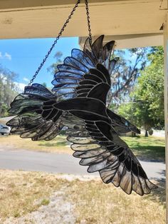 a glass bird hanging from the side of a house