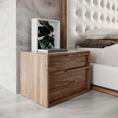 a bed with a white headboard and a wooden night stand on top of it