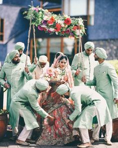 a group of men and women dressed in green standing around a woman on a swing