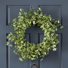 a wreath hanging on the front door of a house with an old fashioned wooden handle