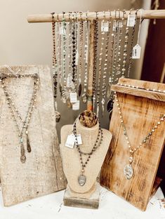 three necklaces are on display in front of two wooden boxes and one is hanging from a rope