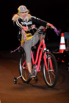 a woman riding on the back of a pink bike