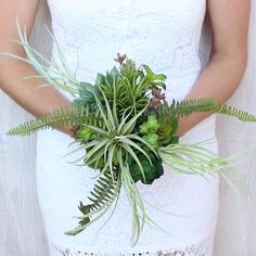 a woman in a white dress holding a bouquet of plants